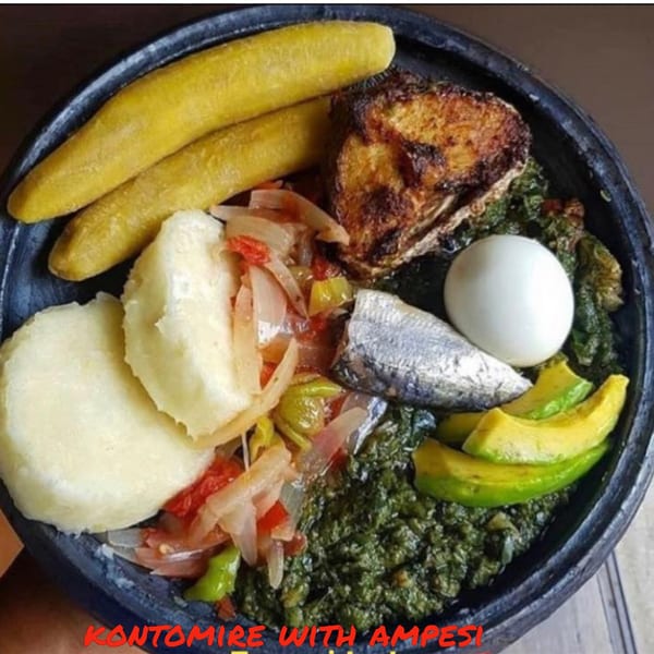A close-up of a traditional African dish with plantains, fish, egg, avocado, and green stew.