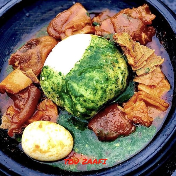 Tou Zaafi, an African dish with green and white fufu, meat, tripe, and a boiled egg.
